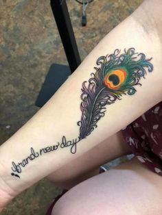 a woman's arm with a tattoo that reads happy new day and a peacock on it