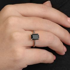 a woman's hand wearing a ring with an emerald stone on the middle finger