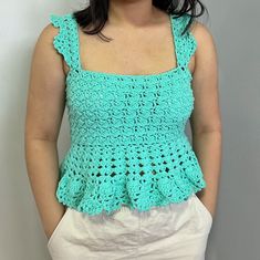 a woman standing in front of a wall wearing a blue top with crochet