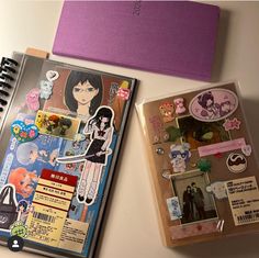 two notebooks sitting next to each other with stickers on them and a notepad