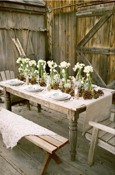 the table is set with white flowers and pine cones