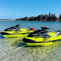 two yellow and black jet skis sitting in the water next to each other on a sunny day