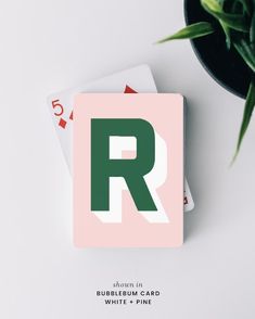 playing cards with the letter r on them next to a potted plant and card deck