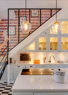 a kitchen with white cabinets and black and white checkered flooring, lights hanging from the ceiling