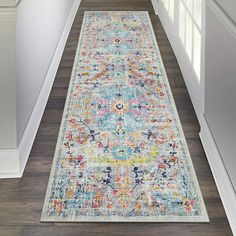 a long hallway with an area rug on the floor and white trim around the door