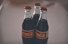 two coca cola bottles sitting on top of a counter