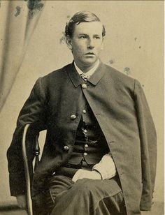 an old black and white photo of a man sitting in a chair with his hands on his hips