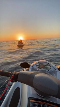 the sun is setting over the ocean with a boat in the water and another boat out to sea