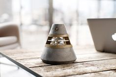 an apple laptop sitting on top of a wooden table next to a stone bell shaped object