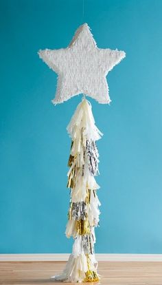 a white star hanging from a string on top of a wooden floor next to a blue wall