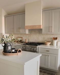 a kitchen with white cabinets and an island in front of a stove top oven, potted plant on the counter