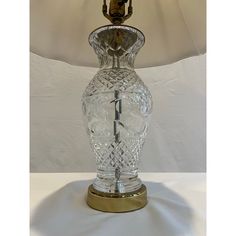 a glass table lamp with a gold base and shade on it's side,