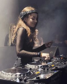 a woman in headphones is playing music on a dj's turntables