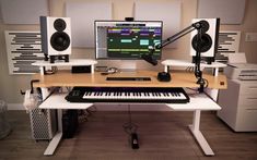 a computer desk with a keyboard, monitor and speakers on it in an office setting