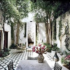 an outdoor dining area with black and white tile flooring, potted plants on the table