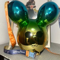 a green mickey mouse helmet on top of a metal shelf next to a photo frame