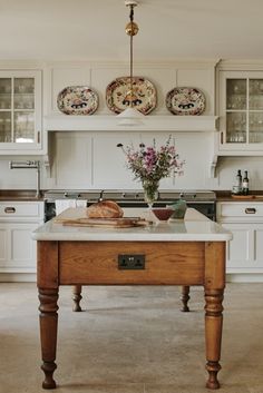 a kitchen with an island in the middle and plates on the back wall above it