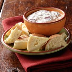 a bowl of dip and chips on a plate with a red napkin next to it