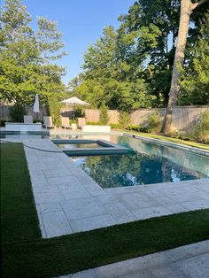 an empty swimming pool surrounded by grass and trees