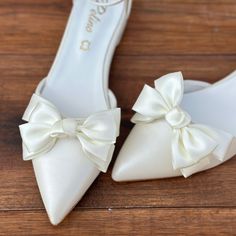 a pair of white shoes with bows on them