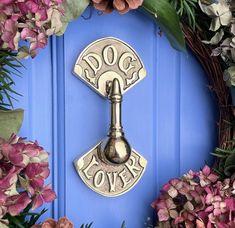 a blue door with a dog lover key and wreath on it, surrounded by flowers