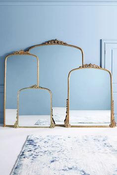 three mirrors sitting next to each other on top of a white rug in front of a blue wall