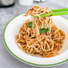 a white plate topped with noodles and chopsticks next to a cup of coffee