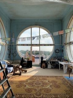 a living room filled with furniture and large round windows next to a rug on the floor