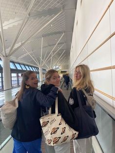 two women standing next to each other in an airport terminal with bags on their backs