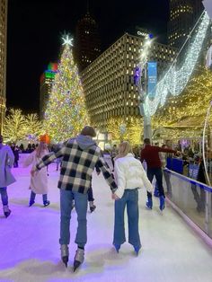 people skating on an ice rink at night with christmas lights in the city behind them