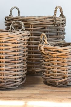 three wicker baskets sitting on top of a wooden table next to each other with handles