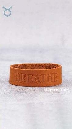 a leather bracelet with the words breathe on it, sitting on top of a table