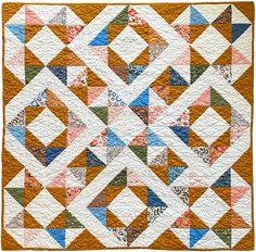 a quilt with many different colors and shapes on the front, along with an orange background