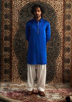 Elevate your style with our versatile blue Pathani mens kurta set, featuring subtle embroidery on the placket. Paired with a classic white salwar, this outfit is perfect for mehendi, festive occasions, or casual gatherings. Effortlessly stylish, it’s a must-have addition to your wardrobe. Blue Kurta With Traditional Drape For Ceremonies, Blue Naqshi Straight Kurta Traditional Wear, Traditional Blue Kurta With Naqshi, Blue Bollywood Kurta For Traditional Ceremonies, Blue Long Sleeve Kurta With Naqshi, Blue Traditional Wear With Naqshi Drape, Blue Traditional Wear With Naqshi, Blue Kurta For Eid And Traditional Ceremonies, Traditional Blue Salwar Kameez With Naqshi