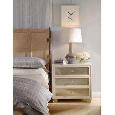 a bedroom with a bed, nightstand and lamp on the side table in front of it