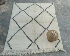 a white rug with a black diamond pattern and a shell on the floor next to it