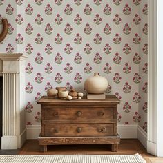 a living room with floral wallpaper and a wooden dresser in front of a fireplace