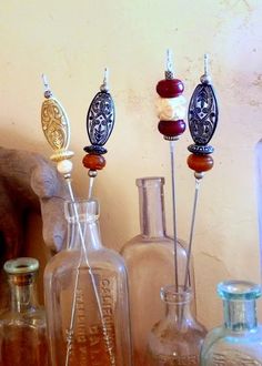 three glass bottles are sitting next to each other on a table with some beads in them