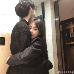 a man hugging a woman in front of a mirror while standing next to a door