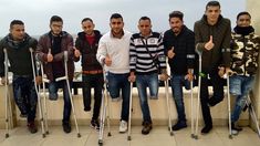 a group of men standing next to each other holding crutches on top of a roof