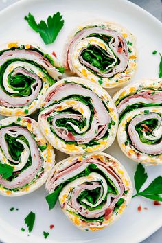 a white plate topped with rolls filled with meat and veggies