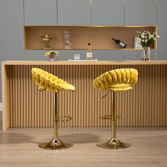 two yellow chairs sitting on top of a wooden floor in front of a kitchen counter