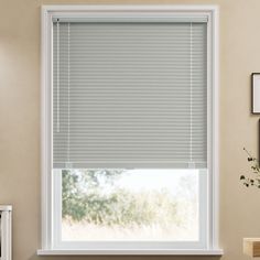 a living room with a window covered in blinds and pictures on the wall behind it