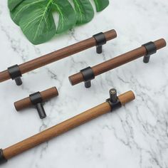 four pieces of wood with black handles on a marble counter top next to a green plant