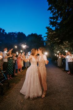 a bride and groom kissing while holding sparklers in their hands at the end of their wedding day