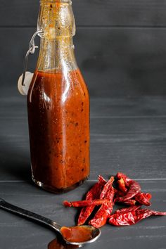 a bottle filled with sauce next to some chili peppers