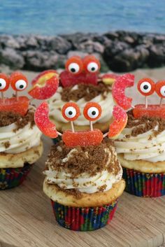 cupcakes decorated with googly eyes and candies on a wooden platter