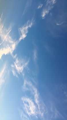 an airplane flying high in the sky with some clouds