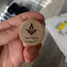 a person holding a small wooden badge with an masonic symbol on it's side