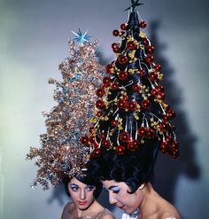 two women standing next to each other in front of a christmas tree with ornaments on it